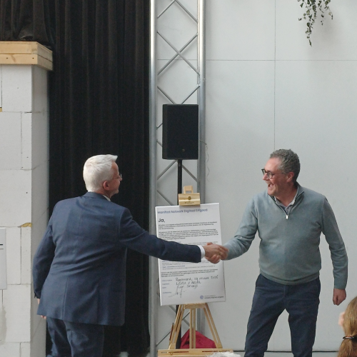 Ondertekening van het een manifest met een handdruk bezegeld door twee mensen.