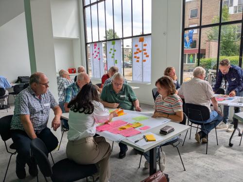 Werkbijeenkomst met groepen aan tafels met post-its