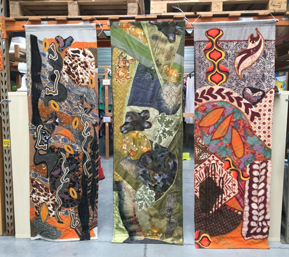 Foto van drie textiel wand werken die in een industriële omgeving hangen 