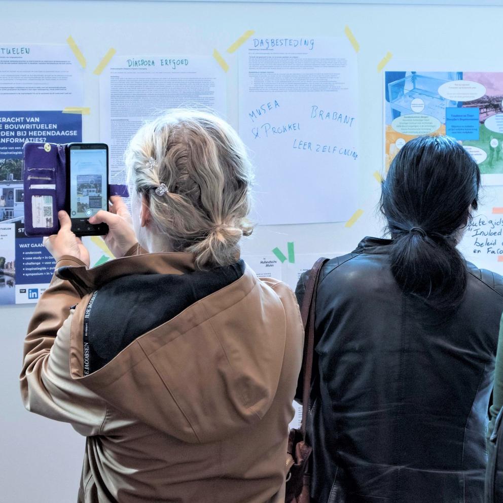 Twee mensen kijken naar een muur met flyers en informatie