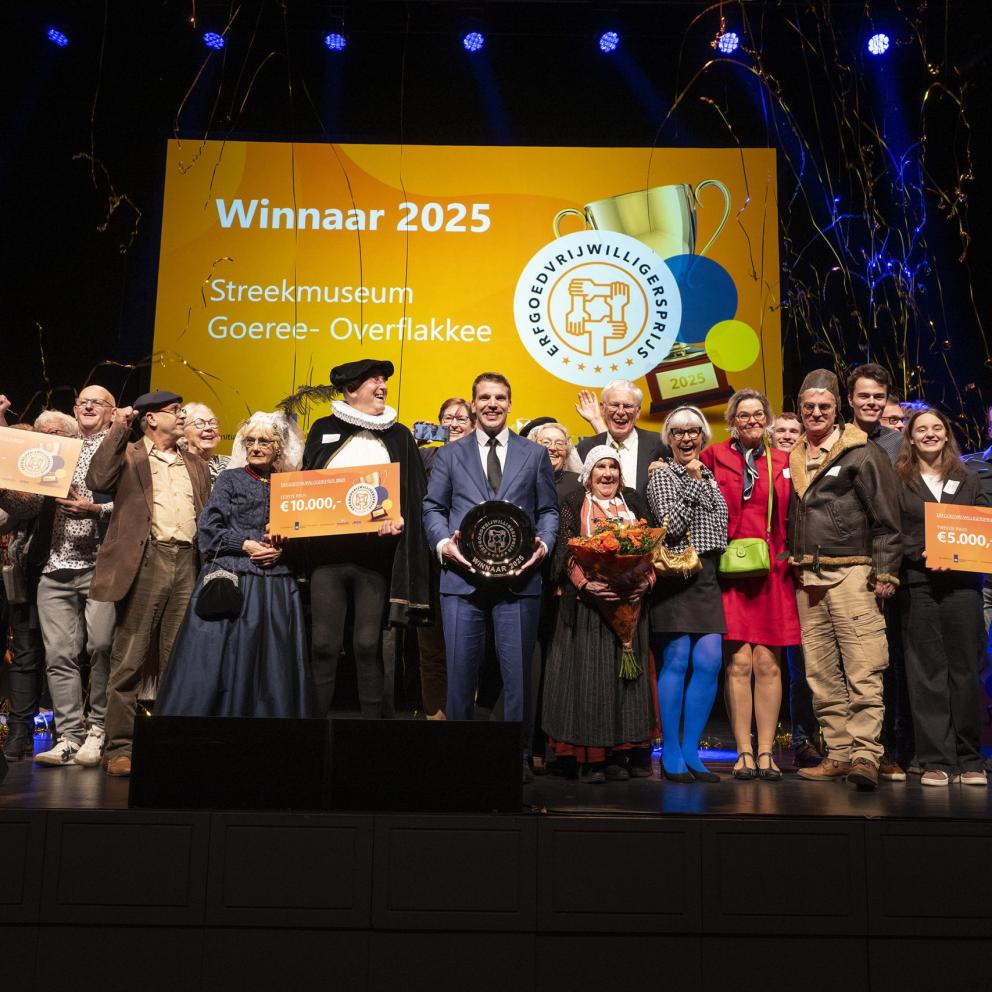 Toneelgroep van het Streekmuseum Goeree-Overflakkee, Winnaars erfgoedvrijwilligersprijs 2025. Een groep mensen, deels in kostuums, die op een podium de prijs in ontvangst nemen.