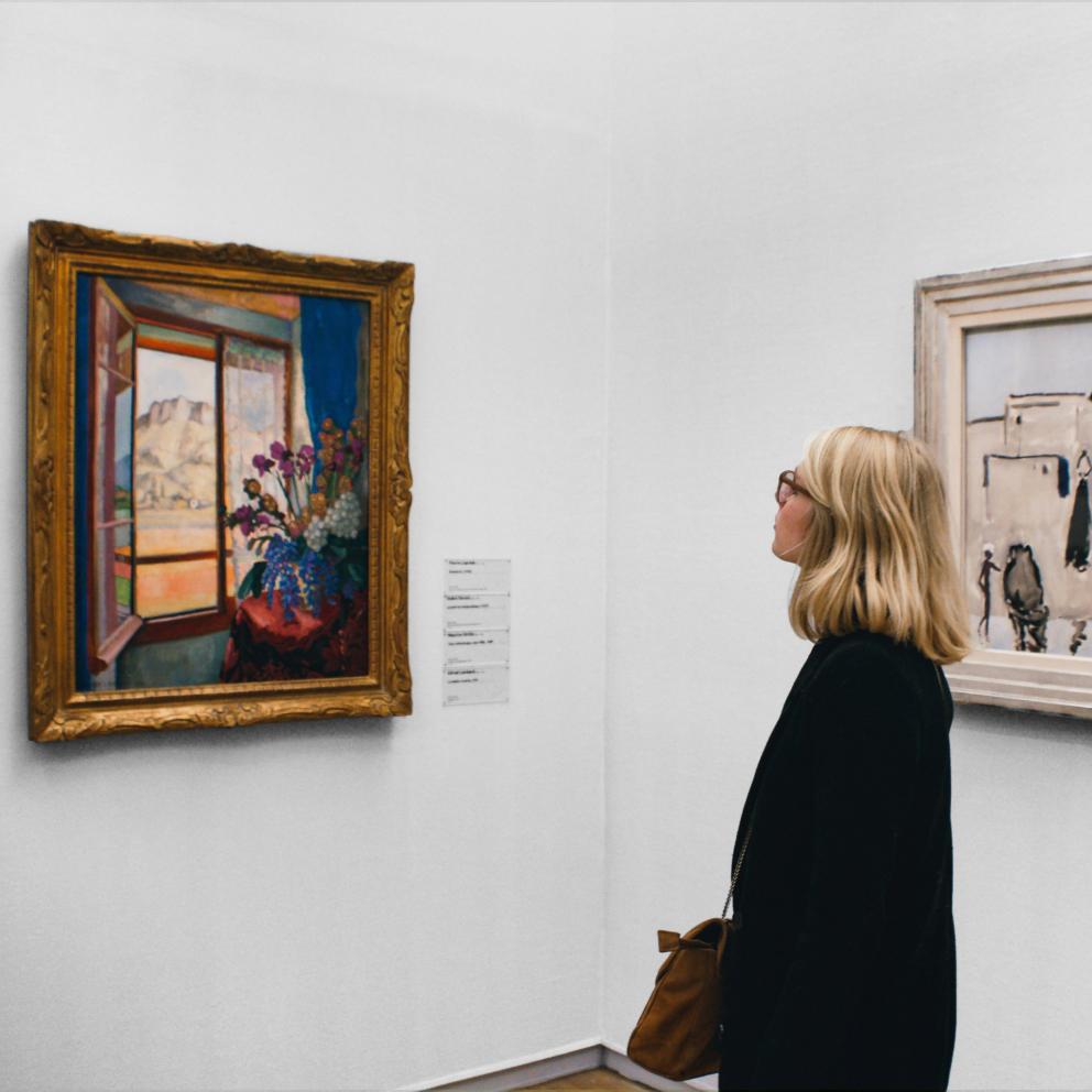 Een vrouw kijkt naar schilderij in een Museum Pauline Loroy